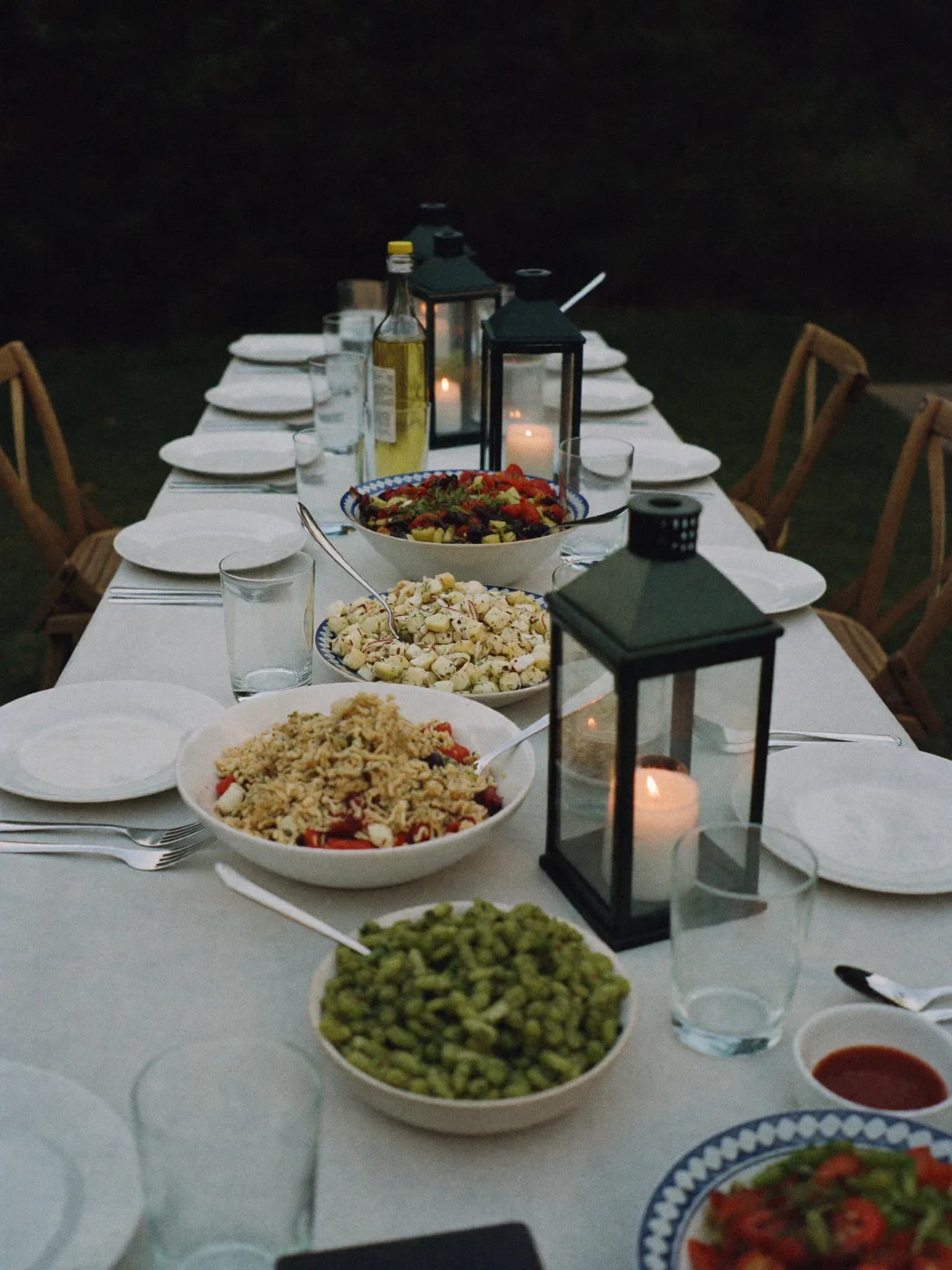 AI-genereret: Havebord med lanterner, salater og glas om aftenen.