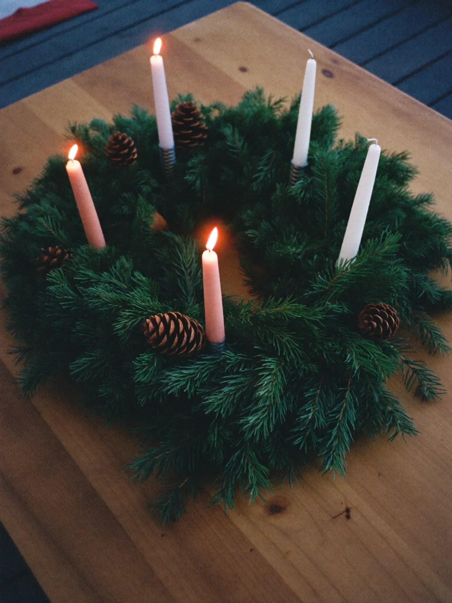 AI-genereret: Adventskrans med fire brændende lys på et træbord.